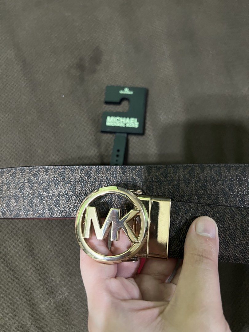 Michael Kors Reversible Belt Brown Logo Red (Category: Belts) located in Valenzuela. Submitted by decluttering.manila (Listing ID 1467089385, Image 1). Description: - Brand: Michael Kors - Design: Reversible (Brown signature monogram on side 1, Solid red leather on side 2) - Hardware: Gold-tone round MK logo buckle - Condition: Good pre-loved condition with minor wear around the punch holes on the red side - Versatile 2-in-1 accessory to elevate 