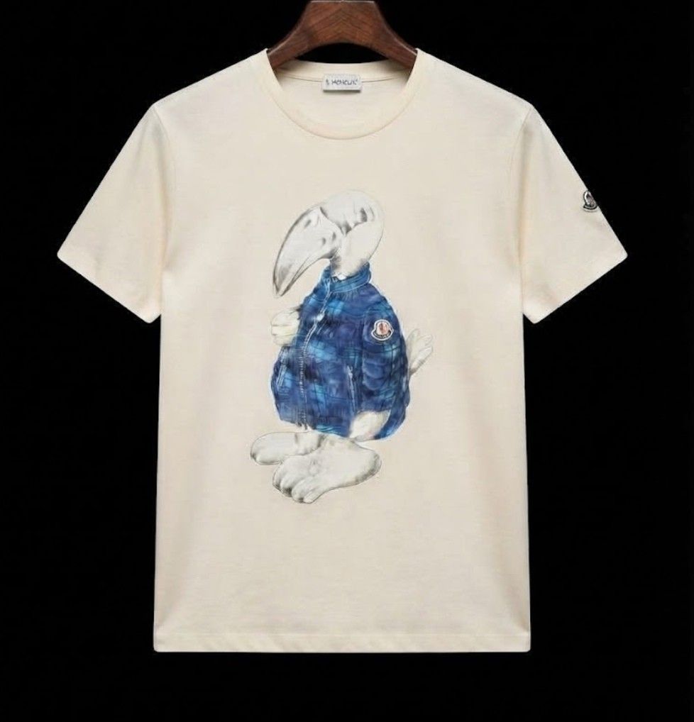 Moncler Graphic Dodo Bird Tee (Category: Shirts) located in Donsol. Submitted by saksthriftavenuebyluckymaria8 (Listing ID 1466977453, Image 2). Description: - Brand: Moncler - Color: off white - Design: Dodo bird graphic on front with sleeve logo patch and tricolor neckline tab - Fit: Short sleeves, classic crew neck - Material: Premium soft cotton, durable stitching - Condition: Clean, crisp prints, well-maintained size xl fits L chest 21 in ar