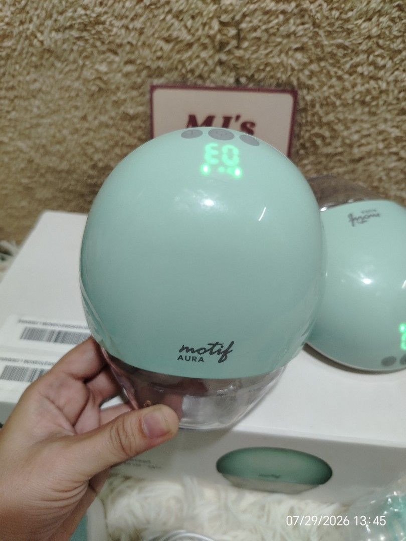 Motif Aura Wearable Breast Pump Set (Category: Breastfeeding & Bottle Feeding) located in Pulilan. Submitted by mjbabyproductsshop (Listing ID 1467042010, Image 3). Description: - Brand: Motif Aura - Type: Double wearable breast pump - Color: Mint green - Condition: Complete set with original box and manual - Included: 2 pump motors, collection containers, charging cables, and extra parts in sealed bags - Features: Clear digital display screens, 