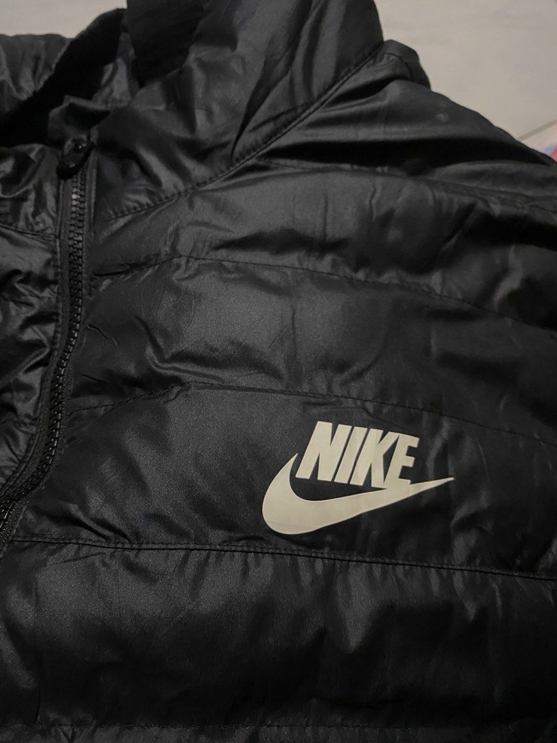 Nike Black Puffer Jacket Size XXL (Category: Coats, Jackets and Outerwear) located in Iloilo. Submitted by laughthrift_goods (Listing ID 1467105727, Image 3). Description: Black Nike puffer jacket in size XXL. Made in Vietnam. 100% polyester body, lining, and fill. Full front zip closure with Nike logo zipper pull. White Nike logo printed on the left chest. Quilted design throughout. High collar. Interior tag shows sizing details and care instruc
