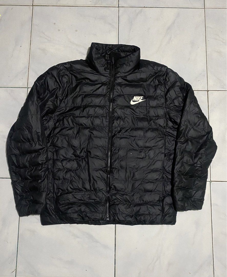 Nike Black Puffer Jacket Size XXL (Category: Coats, Jackets and Outerwear) located in Iloilo. Submitted by laughthrift_goods (Listing ID 1467105727, Image 1). Description: Black Nike puffer jacket in size XXL. Made in Vietnam. 100% polyester body, lining, and fill. Full front zip closure with Nike logo zipper pull. White Nike logo printed on the left chest. Quilted design throughout. High collar. Interior tag shows sizing details and care instruc