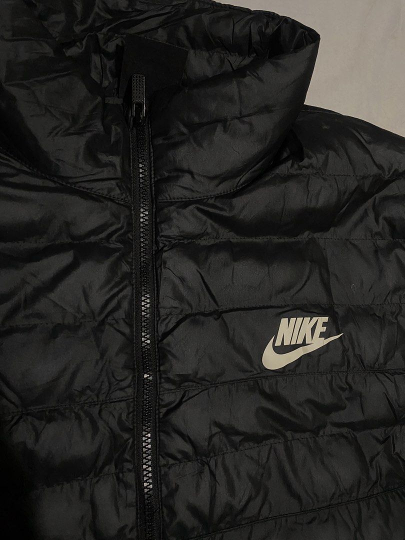 Nike Black Puffer Jacket Size XXL (Category: Coats, Jackets and Outerwear) located in Iloilo. Submitted by laughthrift_goods (Listing ID 1467105727, Image 2). Description: Black Nike puffer jacket in size XXL. Made in Vietnam. 100% polyester body, lining, and fill. Full front zip closure with Nike logo zipper pull. White Nike logo printed on the left chest. Quilted design throughout. High collar. Interior tag shows sizing details and care instruc