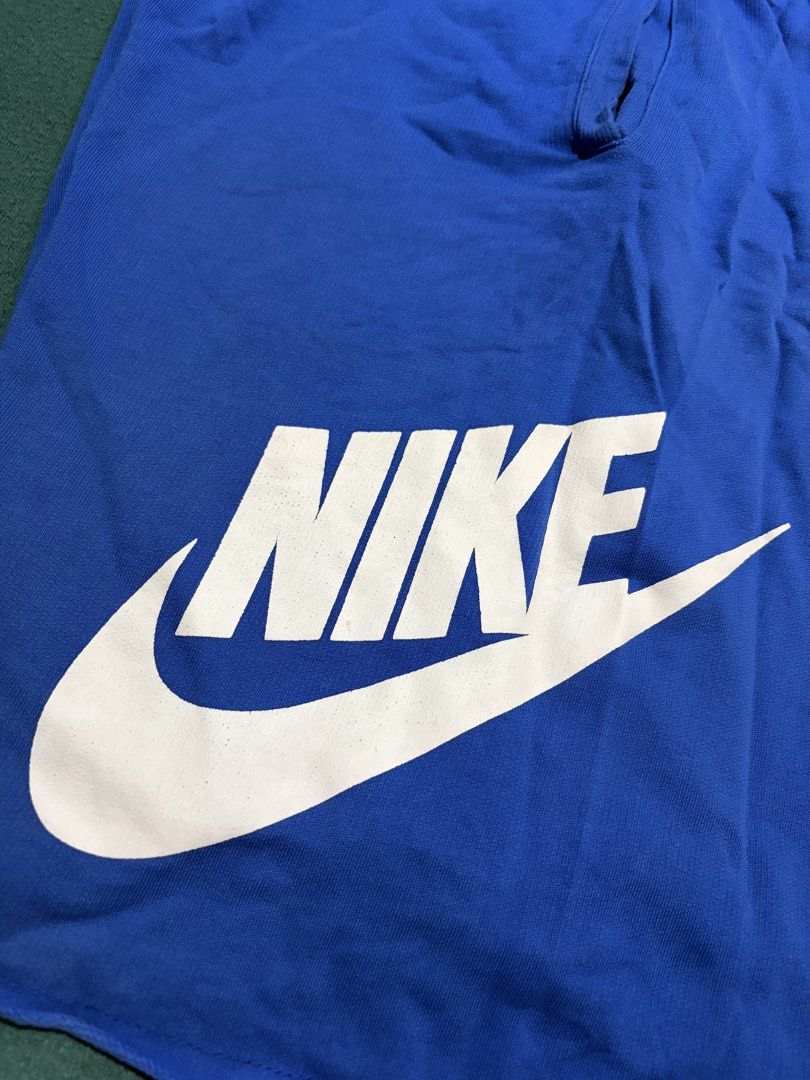 Nike Blue Drawstring Shorts With Big Logo Print (Category: Shorts) located in Guihulngan. Submitted by fbthriftgoodsniace (Listing ID 1467095034, Image 2). Description: - Brand: Nike - Color: Bright blue with large white graphic print on left leg - Material: Comfortable cotton - Fit: Relaxed fit, ideal for lounging or working out - Features: Elastic waistband with white adjustable drawstring and trendy raw cut hem - Measurements: Waist across ~16