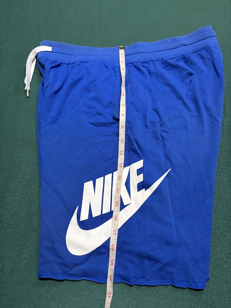 Nike Blue Drawstring Shorts With Big Logo Print (Category: Shorts) located in Guihulngan. Submitted by fbthriftgoodsniace (Listing ID 1467095034, Image 3). Description: - Brand: Nike - Color: Bright blue with large white graphic print on left leg - Material: Comfortable cotton - Fit: Relaxed fit, ideal for lounging or working out - Features: Elastic waistband with white adjustable drawstring and trendy raw cut hem - Measurements: Waist across ~16