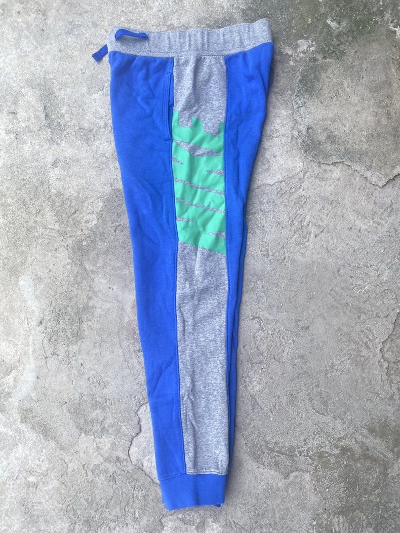 Nike Blue Grey Sweatpants Size M (Category: Joggers) located in Manila. Submitted by keenriver-4b36 (Listing ID 1467154079, Image 2). Description: - Brand: Nike - Style: Sweatpants in blue and grey with green graphic print down the side panel - Fit & Size: Standard fit, Size M - Material: 80% cotton, 20% polyester blend (Made in Cambodia) - Features: Elastic waistband with blue drawstring, convenient side pockets - Condition: Clean fabric inside 