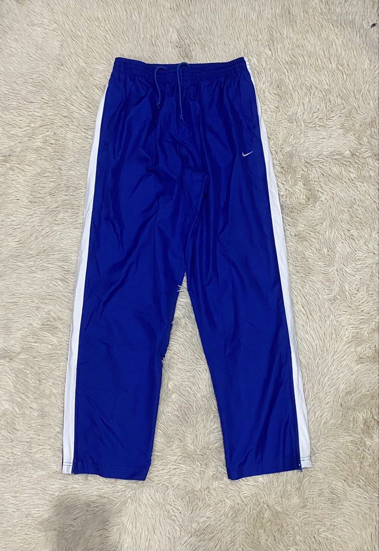 Nike Blue White Stripe Track Pants Size M (Category: Joggers) located in Antipolo. Submitted by switchneighborhood (Listing ID 1467117052, Image 2). Description: - Brand: Nike - Style: Track pants with white side stripes - Color: Blue with embroidered white Swoosh logo on the thigh - Size: Medium - Material: Lightweight nylon with mesh inner lining - Origin: Made in Vietnam - Features: Elastic waistband with adjustable drawstring and lower leg zi