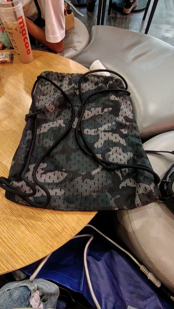 Nike Camouflage Print Gym Sack Drawstring Backpack (Category: Backpacks) located in Manila. Submitted by purediamond888 (Listing ID 1467047260, Image 3). Description: - Brand: Nike - Design: All-over dark camouflage print with vertical branding - Material: Durable, mesh-like textured fabric - Closure: Smooth drawstring for easy access - Storage: Handy side zipper pocket for small essentials - Best for: Gym, sports practice, or casual everyday car