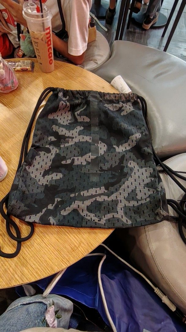 Nike Camouflage Print Gym Sack Drawstring Backpack (Category: Backpacks) located in Manila. Submitted by purediamond888 (Listing ID 1467047260, Image 2). Description: - Brand: Nike - Design: All-over dark camouflage print with vertical branding - Material: Durable, mesh-like textured fabric - Closure: Smooth drawstring for easy access - Storage: Handy side zipper pocket for small essentials - Best for: Gym, sports practice, or casual everyday car