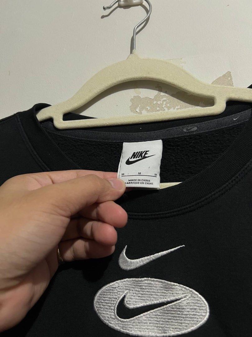 Nike Swoosh Oval Logo Black Sweatshirt (Category: Coats, Jackets and Outerwear) located in Bacoor. Submitted by theneedwash (Listing ID 1467132933, Image 2). Description: - Brand: Nike - Style Code: DM5461-010 - Size: Medium - Color: Black - Design: Embroidered layered Swoosh & oval logo on chest, oversized printed logo on back shoulders - Details: Ribbed crew neck, cuffs, and hem with thick fleece interior.