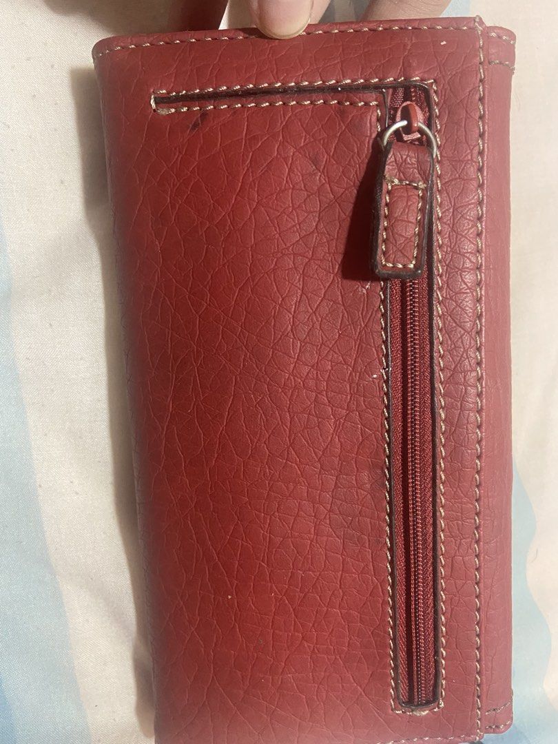 Nine West Red Leather Long Wallet (Category: Wallets & Card holders) located in Las Pinas. Submitted by 22nellie28 (Listing ID 1467125633, Image 2). Description: - Brand: Nine West - Material: Red textured leather - Closure: Silver buckle on front flap - Exterior: Convenient back zippered pocket - Interior: Multiple card slots, cash compartments, and deep red fabric lining - Condition: Clean stitching and well-maintained.