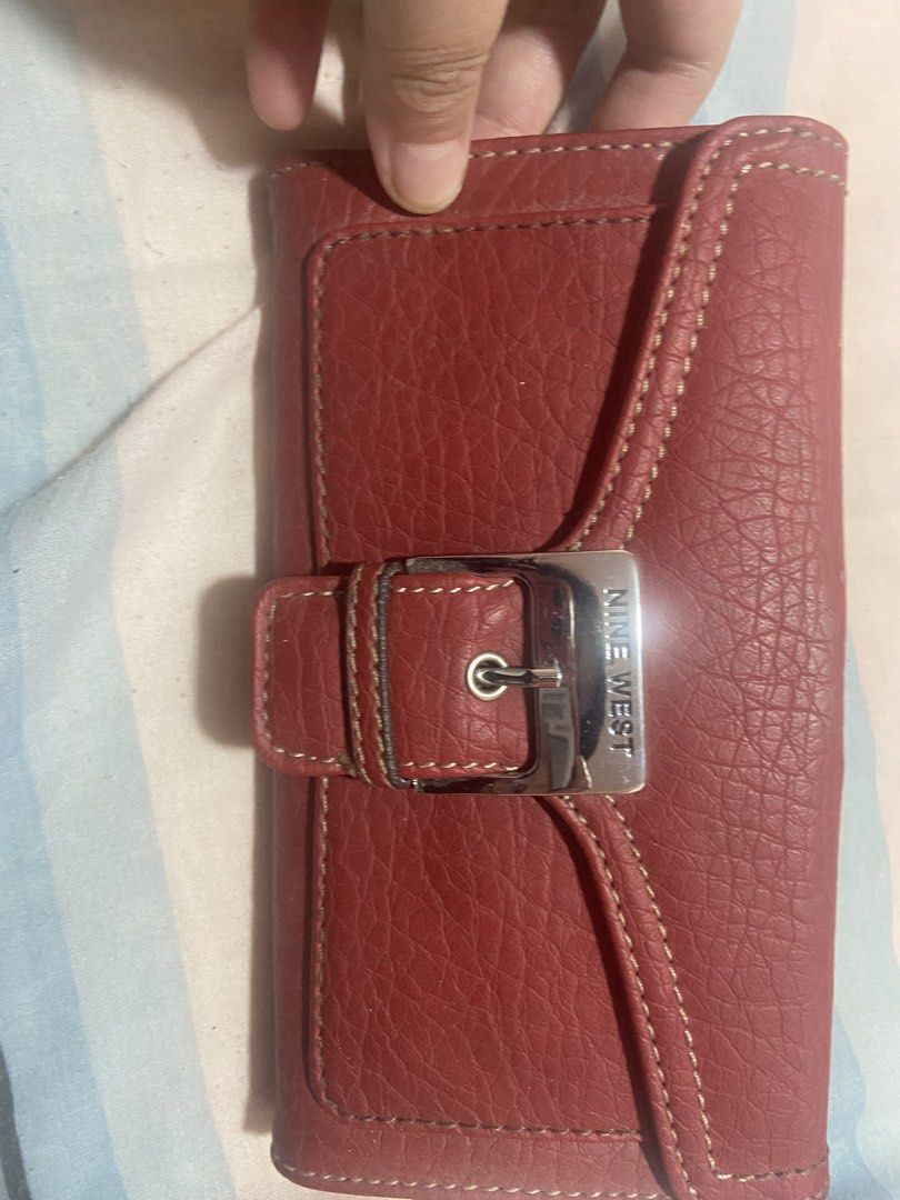 Nine West Red Leather Long Wallet (Category: Wallets & Card holders) located in Las Pinas. Submitted by 22nellie28 (Listing ID 1467125633, Image 1). Description: - Brand: Nine West - Material: Red textured leather - Closure: Silver buckle on front flap - Exterior: Convenient back zippered pocket - Interior: Multiple card slots, cash compartments, and deep red fabric lining - Condition: Clean stitching and well-maintained.
