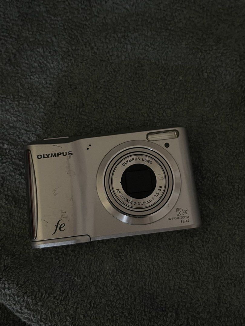 Olympus FE-47 Digital Camera (Category: Cameras) located in Candaba. Submitted by xanddi (Listing ID 1467037774, Image 2). Description: - Model: Olympus FE-47 Compact Digital Camera (Silver) - Lens: 5x optical zoom (6.3-31.5mm focal length) - Features: Built-in flash, rear LCD screen with standard navigation buttons, bottom tripod mount - Condition: Moderate wear and scratches on the exterior body from previous use ++ ALL WORKING. - Power: Uses d