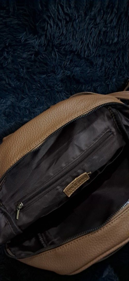 Parisian Brown Faux Leather Backpack (Category: Backpacks) located in Agdangan. Submitted by crinee_ (Listing ID 1467151790, Image 3). Description: - Brand/Style: Parisian brown faux leather backpack - Exterior: Textured pebble finish with trendy vertical pleat front pocket - Interior: Dark brown fabric lining with 1 zip pocket and slip compartments - Closure: Secure double zipper - Carry options: Adjustable back straps and top handle - Condition