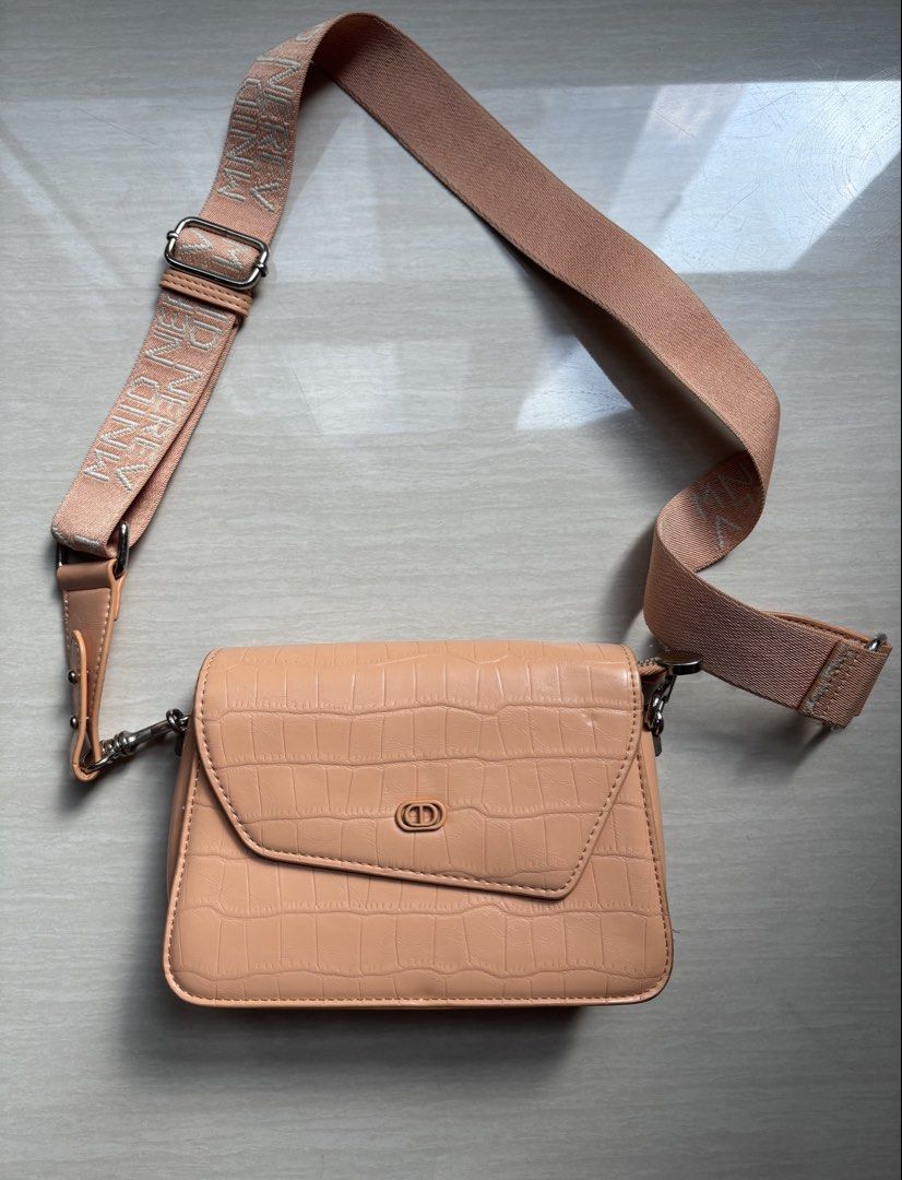 Peach Croc Pattern Crossbody Bag with Wide Strap (Category: Cross-body Bags) located in Makati City. Submitted by bittersweet818ta (Listing ID 1467155313, Image 1). Description: - Trendy peach crossbody bag with faux crocodile skin texture - Secure flap closure with snap buttons and subtle logo detail - Thick, adjustable woven strap featuring a stylish repeated text pattern - Silver-tone hardware for a modern finish - Organized interior with mult