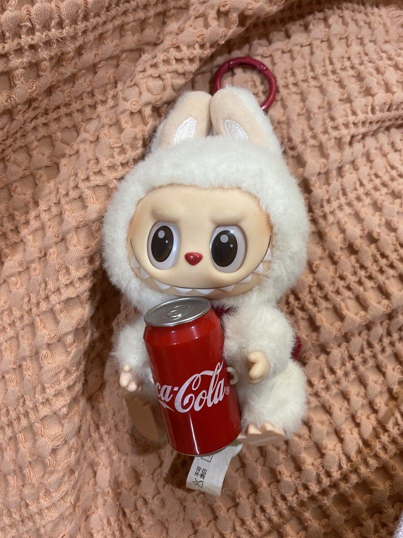 POPMART LABUBU COKE CAN (no box :() (Category: Plushies & Soft Toys) located in Manila. Submitted by ysabaw (Listing ID 1466982360, Image 2). Description: -My kuya bought for me, but not my style anymore - Authentic Pop Mart x Coca-Cola Labubu plush pendant (No BOX) - Adorable fluffy white bunny hat design holding a mini red Coca-Cola can - Features a convenient red keyring at the top - Authenticity markings stamped on the foot with original tags
