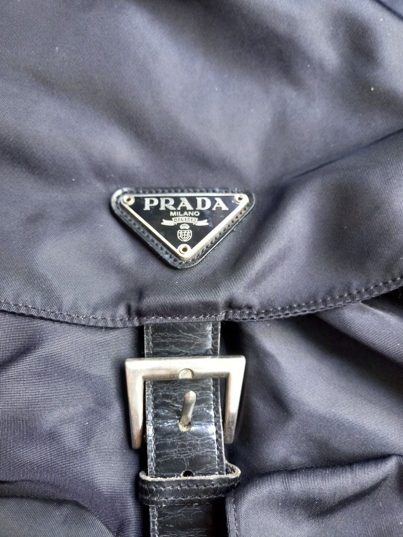 Prada Black Nylon Backpack with Leather Straps and Buckles (Category: Backpacks) located in Davao. Submitted by kirk214red-50020 (Listing ID 1466982797, Image 2). Description: - Brand: Prada - Material: Durable black nylon with leather trim - Hardware: Silver-tone with engraved Prada lettering - Closure: Drawstring top and front flap with buckled strap - Pockets: Two front pockets with secure buckle closures - Straps: Adjustable fabric shoulder s