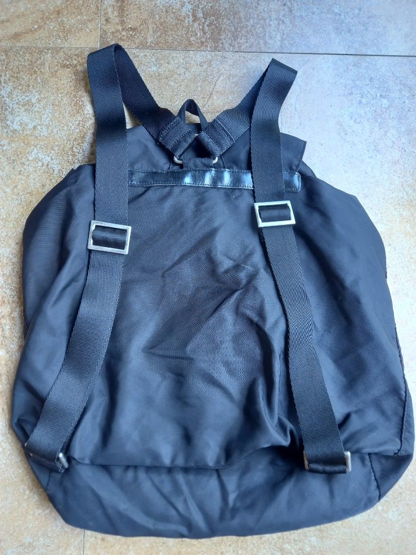 Prada Black Nylon Backpack with Leather Straps and Buckles (Category: Backpacks) located in Davao. Submitted by kirk214red-50020 (Listing ID 1466982797, Image 3). Description: - Brand: Prada - Material: Durable black nylon with leather trim - Hardware: Silver-tone with engraved Prada lettering - Closure: Drawstring top and front flap with buckled strap - Pockets: Two front pockets with secure buckle closures - Straps: Adjustable fabric shoulder s