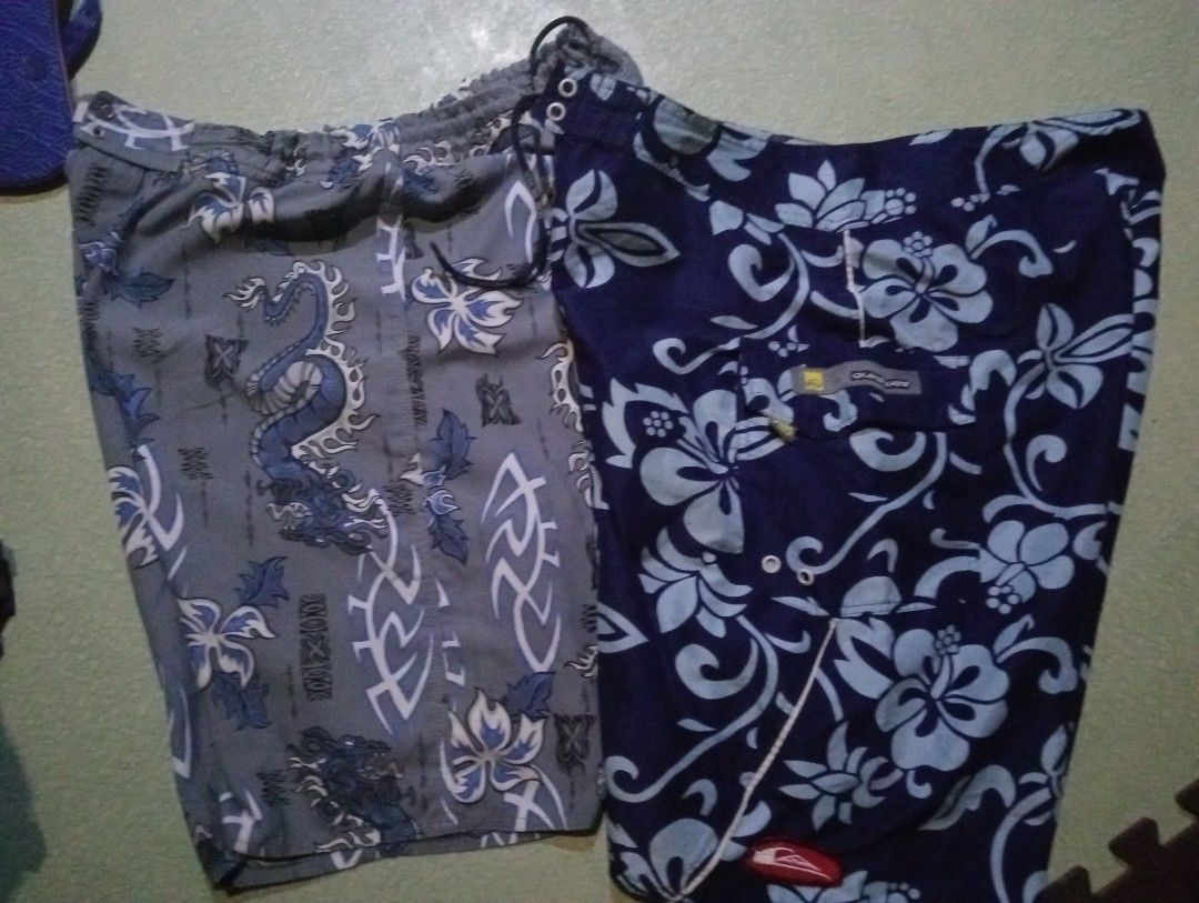 Quiksilver and Riper (Category: Swim Trunks & Board Shorts) located in Quezon City. Submitted by shawnyysh (Listing ID 1467090141, Image 1). Description: - Bundle of 2 pairs of well-maintained surf shorts for swimming and beach days - Pair 1: Dark blue with light blue floral Hawaiian pattern, velcro leg pocket, and Quiksilver logo tag on the hem - Pair 2: Grey with blue dragons and tribal tattoos, featuring a comfortable elastic waistband with dr