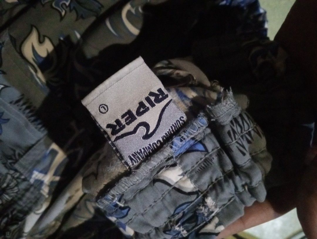 Quiksilver and Riper (Category: Swim Trunks & Board Shorts) located in Quezon City. Submitted by shawnyysh (Listing ID 1467090141, Image 2). Description: - Bundle of 2 pairs of well-maintained surf shorts for swimming and beach days - Pair 1: Dark blue with light blue floral Hawaiian pattern, velcro leg pocket, and Quiksilver logo tag on the hem - Pair 2: Grey with blue dragons and tribal tattoos, featuring a comfortable elastic waistband with dr