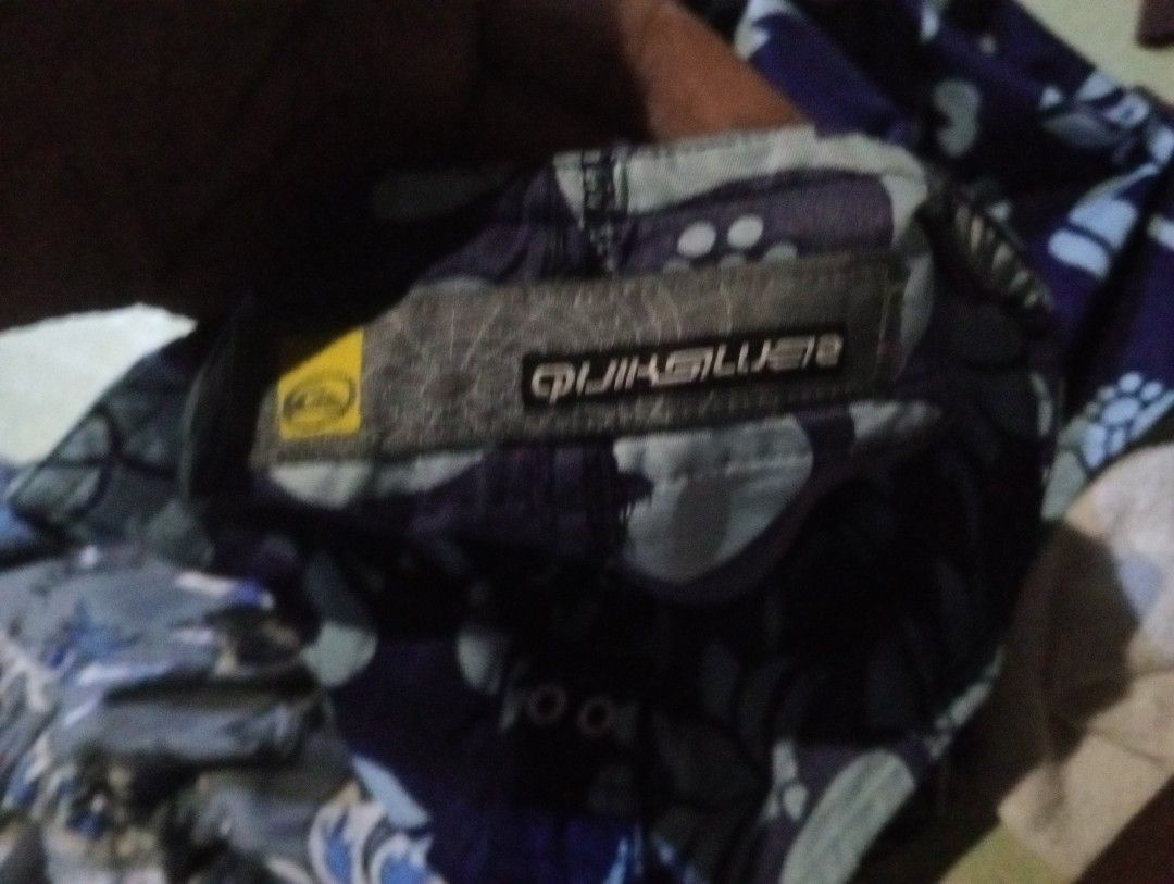 Quiksilver and Riper (Category: Swim Trunks & Board Shorts) located in Quezon City. Submitted by shawnyysh (Listing ID 1467090141, Image 3). Description: - Bundle of 2 pairs of well-maintained surf shorts for swimming and beach days - Pair 1: Dark blue with light blue floral Hawaiian pattern, velcro leg pocket, and Quiksilver logo tag on the hem - Pair 2: Grey with blue dragons and tribal tattoos, featuring a comfortable elastic waistband with dr