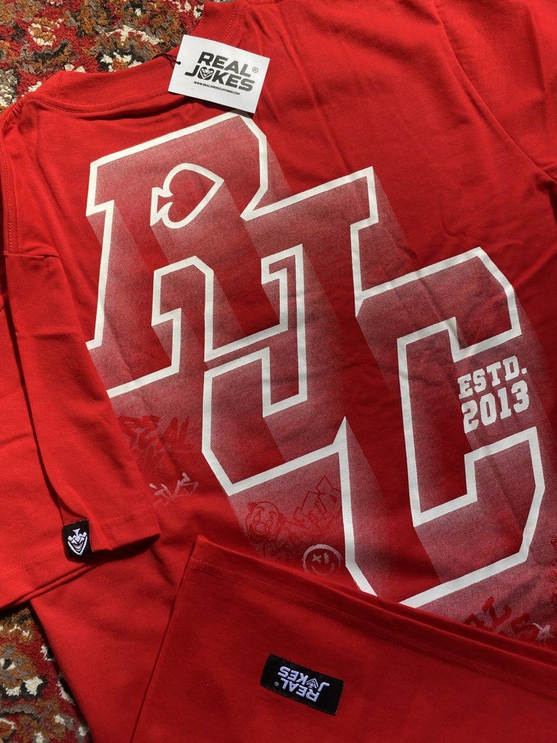 Real Jokes Red Graphic Tee Shirt (Category: Tshirts & Polo Shirts ) located in Manila. Submitted by nastorjeri57541 (Listing ID 1467123628, Image 3). Description: - Brand: Real Jokes (RJC) - Color: Vibrant Red - Size: Large - Design: College-style RJC lettering print on back and front chest - Material: Soft cotton fabric - Features: Crew neck, short sleeves, brand patch labels near hem and sleeve cuff - Condition: Brand new with tag attached at t