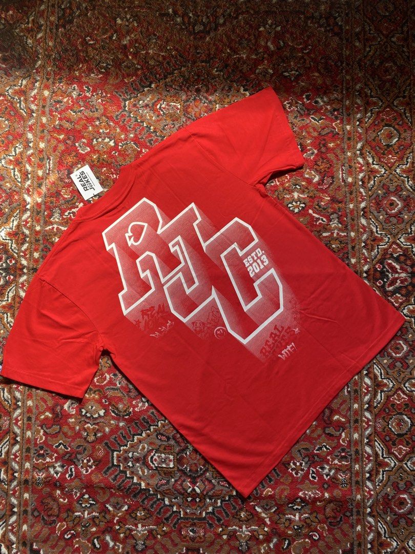 Real Jokes Red Graphic Tee Shirt (Category: Tshirts & Polo Shirts ) located in Manila. Submitted by nastorjeri57541 (Listing ID 1467123628, Image 1). Description: - Brand: Real Jokes (RJC) - Color: Vibrant Red - Size: Large - Design: College-style RJC lettering print on back and front chest - Material: Soft cotton fabric - Features: Crew neck, short sleeves, brand patch labels near hem and sleeve cuff - Condition: Brand new with tag attached at t