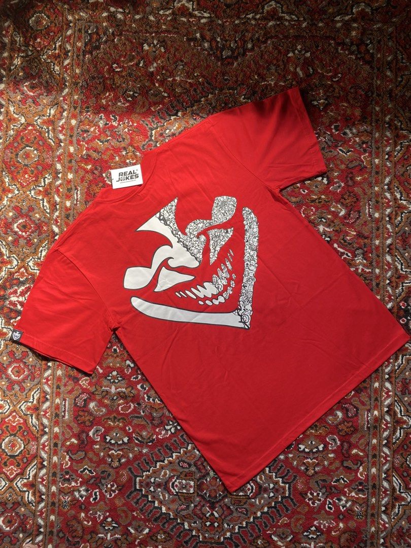 Real Jokes Red Graphic Tee Size L (Category: Tshirts & Polo Shirts ) located in Manila. Submitted by nastorjeri57541 (Listing ID 1467124965, Image 2). Description: - Brand: Real Jokes - Condition: Brand new with tags attached - Size: L - Color: Red - Front Design: Bold white 'REAL JOKES' text graphic with a quirky joker face - Back Design: Large abstract doodle graphic print - Details: Small woven logo label on the left sleeve hem.