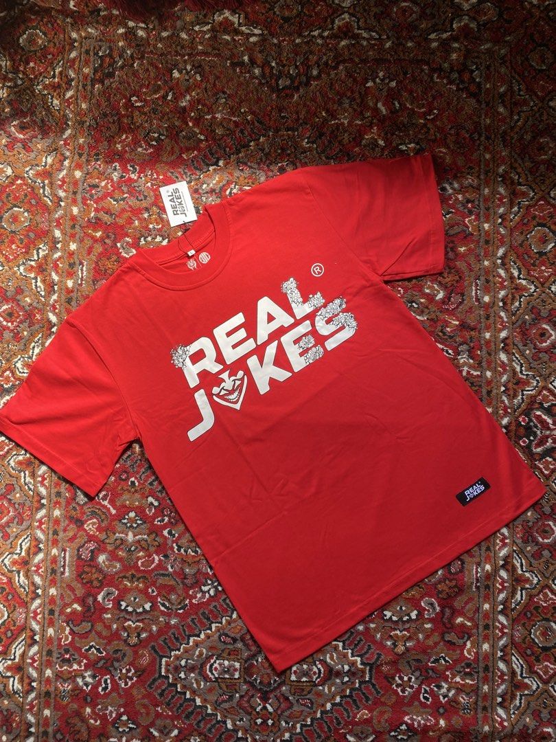 Real Jokes Red Graphic Tee Size L (Category: Tshirts & Polo Shirts ) located in Manila. Submitted by nastorjeri57541 (Listing ID 1467124965, Image 1). Description: - Brand: Real Jokes - Condition: Brand new with tags attached - Size: L - Color: Red - Front Design: Bold white 'REAL JOKES' text graphic with a quirky joker face - Back Design: Large abstract doodle graphic print - Details: Small woven logo label on the left sleeve hem.