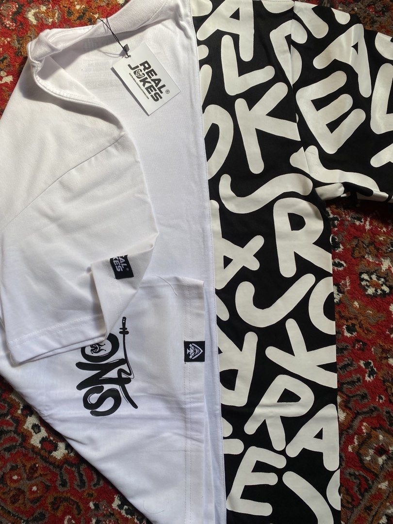 Real Jokes Split Design Typography T-Shirt (Category: Shirts) located in Manila. Submitted by nastorjeri57541 (Listing ID 1467125562, Image 3). Description: - Brand: Real Jokes - Condition: Brand new, never worn, with original tags attached - Design: Unique split design (white on one side, black with bold typography on the other) - Details: Short sleeves, crew neck, graphic print near the bottom hem, small brand tags on sleeve cuff and hem - Perf