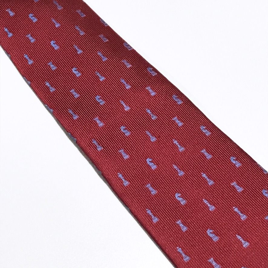 Renoma Chess PiscesTextured Ribbed Red Neck Tie (Category: Ties) located in Taguig. Submitted by retrogaze (Listing ID 1466998220, Image 3). Description: This 100% silk necktie by Renoma features a rich crimson red base woven with a pronounced vertical ribbed texture. The body is decorated with an orderly novelty pattern of miniature chess pieces—including kings, queens, rooks, knights, and bishops—woven in a contrasting periwinkle light blue sil