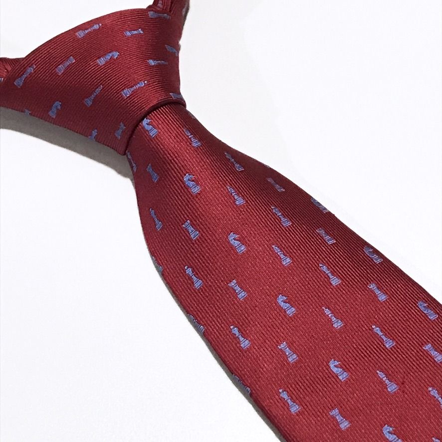 Renoma Chess PiscesTextured Ribbed Red Neck Tie (Category: Ties) located in Taguig. Submitted by retrogaze (Listing ID 1466998220, Image 1). Description: This 100% silk necktie by Renoma features a rich crimson red base woven with a pronounced vertical ribbed texture. The body is decorated with an orderly novelty pattern of miniature chess pieces—including kings, queens, rooks, knights, and bishops—woven in a contrasting periwinkle light blue sil