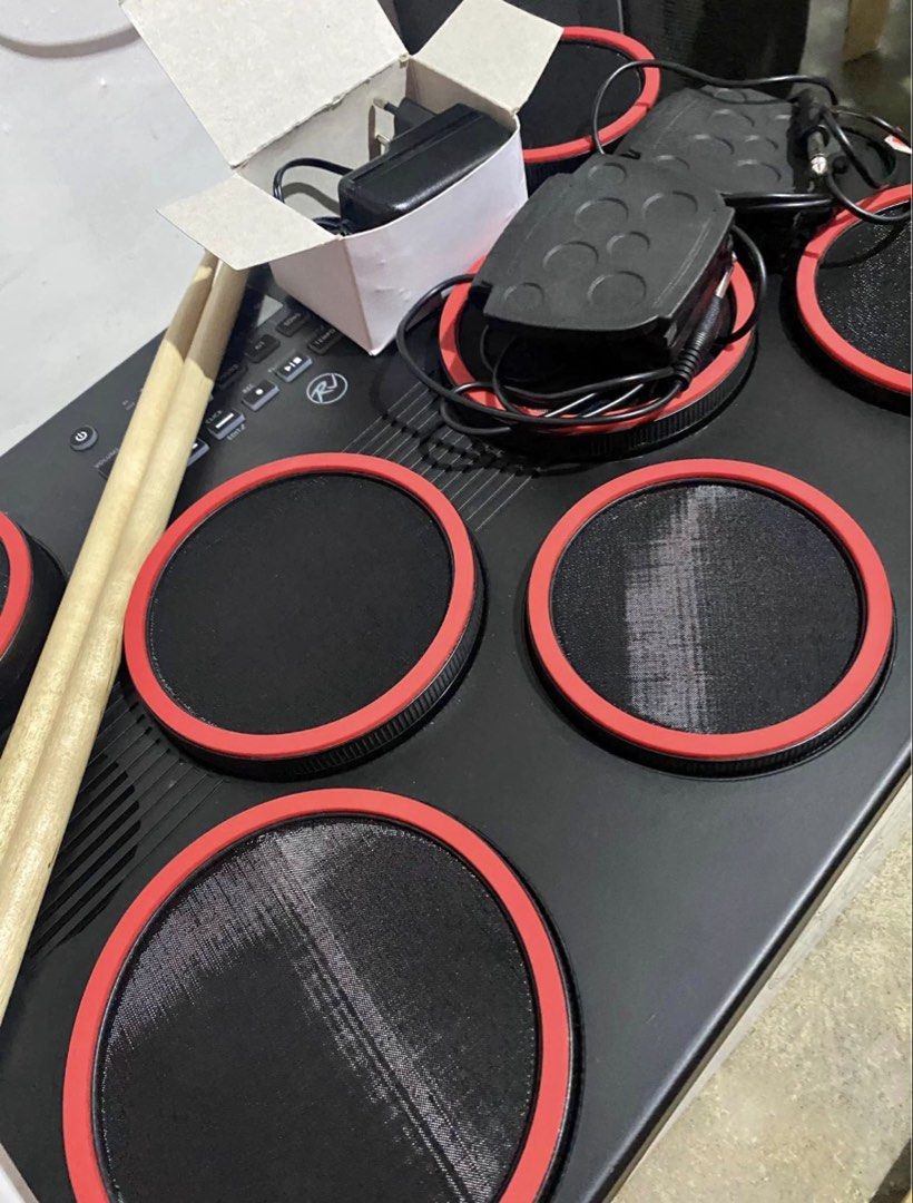 RJ Electronic Portable Drum Pad with Pedals and Sticks (Category: Musical Instruments) located in Paranaque City. Submitted by losangeles10 (Listing ID 1467086521, Image 1). Description: - Brand: RJ - Type: Portable electronic drum pad kit - Condition: Includes original box - Features: Realistic mesh pads with red rims, built-in speakers, and easy-to-use control panel - Inclusions: Drum unit, 2 pedals, power adapter, and wooden drum sticks - Perf
