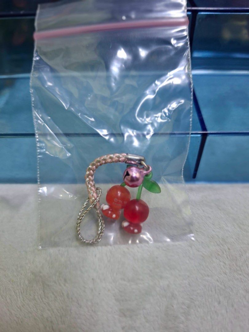 Sanrio Hello Kitty Cherry Strap Charm (Category: Charms) located in Manila. Submitted by janetecson05 (Listing ID 1467061046, Image 2). Description: - Authentic Sanrio phone charm featuring Kitty dressed as adorable cherries - Detailed with a green stem and a small working pink bell - Comes with a durable pink braided strap for easy attachment.