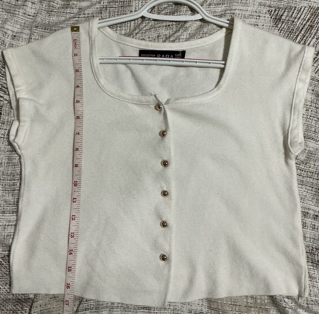 SARA White Knit Button-Up Crop Top (Category: Blouses) located in Quezon City. Submitted by cleaningmomma (Listing ID 1467058241, Image 2). Description: - Style: White knit crop top with short cap sleeves - Details: Square neckline and decorative gold-toned buttons - Material: Soft ribbed fabric with a great stretch - Measurements: ~16.5 inches in length, ~17inches across the chest - Versatility: Perfect basic for layering or warm-weather styling