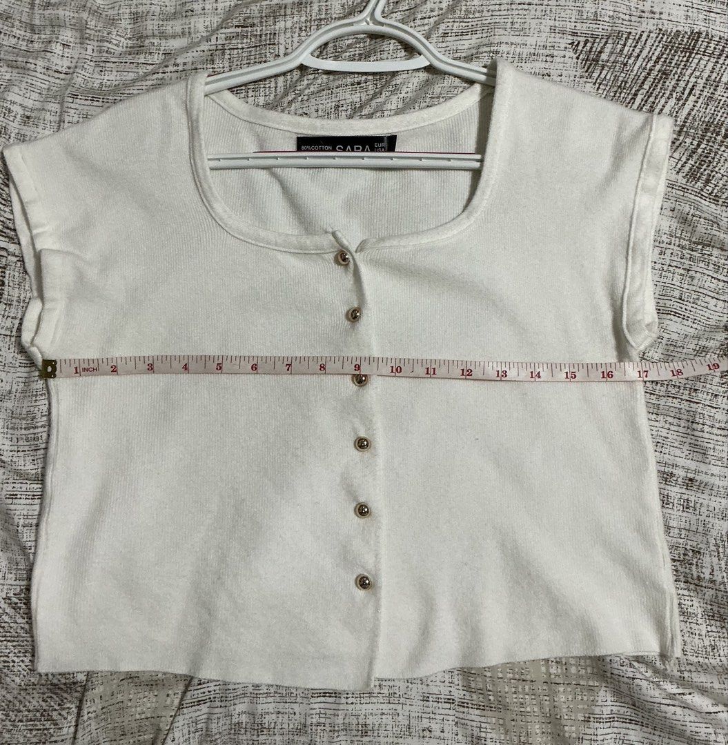 SARA White Knit Button-Up Crop Top (Category: Blouses) located in Quezon City. Submitted by cleaningmomma (Listing ID 1467058241, Image 3). Description: - Style: White knit crop top with short cap sleeves - Details: Square neckline and decorative gold-toned buttons - Material: Soft ribbed fabric with a great stretch - Measurements: ~16.5 inches in length, ~17inches across the chest - Versatility: Perfect basic for layering or warm-weather styling