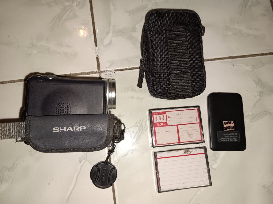 (UNTESTED)Sharp Viewcam Z VL-Z5 Digital Camcorder bundle (Category: Video Cameras) located in Manila. Submitted by caaths_collection (Listing ID 1467140357, Image 3). Description: - AS IS - untested Sharp Viewcam Z VL-Z5 digital video camera package. Includes Sony carrying case, remote control, and two Sony Mini DV cassettes. Hand strap attached. Powers via tapes and accessories included. Vintage gear for retro video projects or collection..