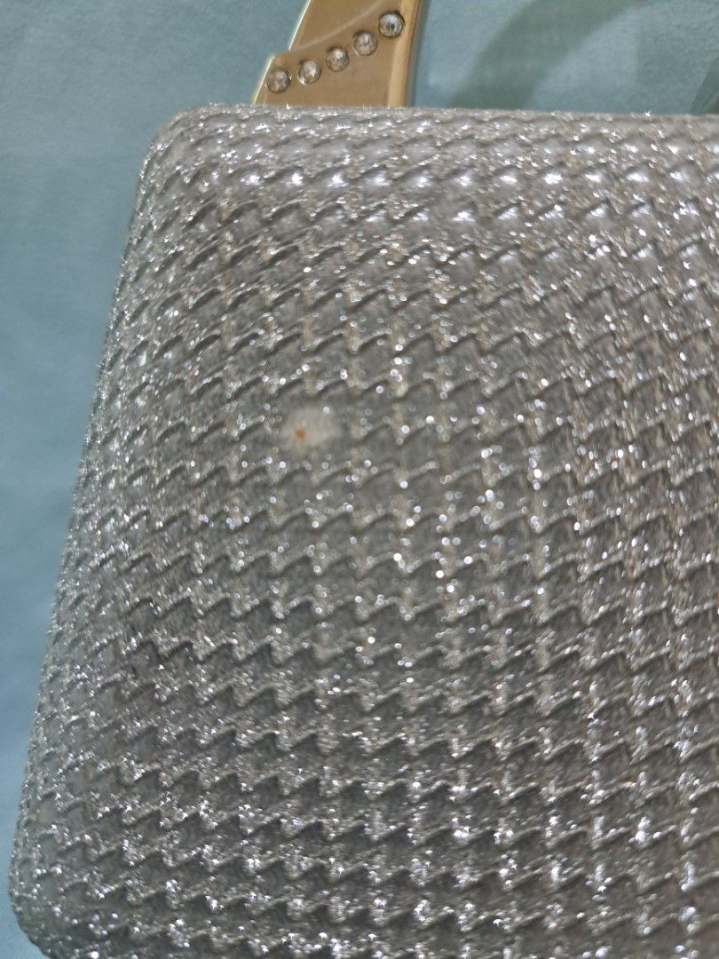 Silver Sparkly Clutch Bag with Metallic Handle and extra chain strap (Category: Clutches) located in Cebu City. Submitted by piakrisia (Listing ID 1467059924, Image 3). Description: - Color: Silver - Material: Textured glitter fabric - Design: Structured box shape with secure metal clasp - Handle: Sturdy metallic arched handle with rhinestone side mounts - Interior: Clean and spacious, silk lining - Condition: Good, used once, with a very tiny st