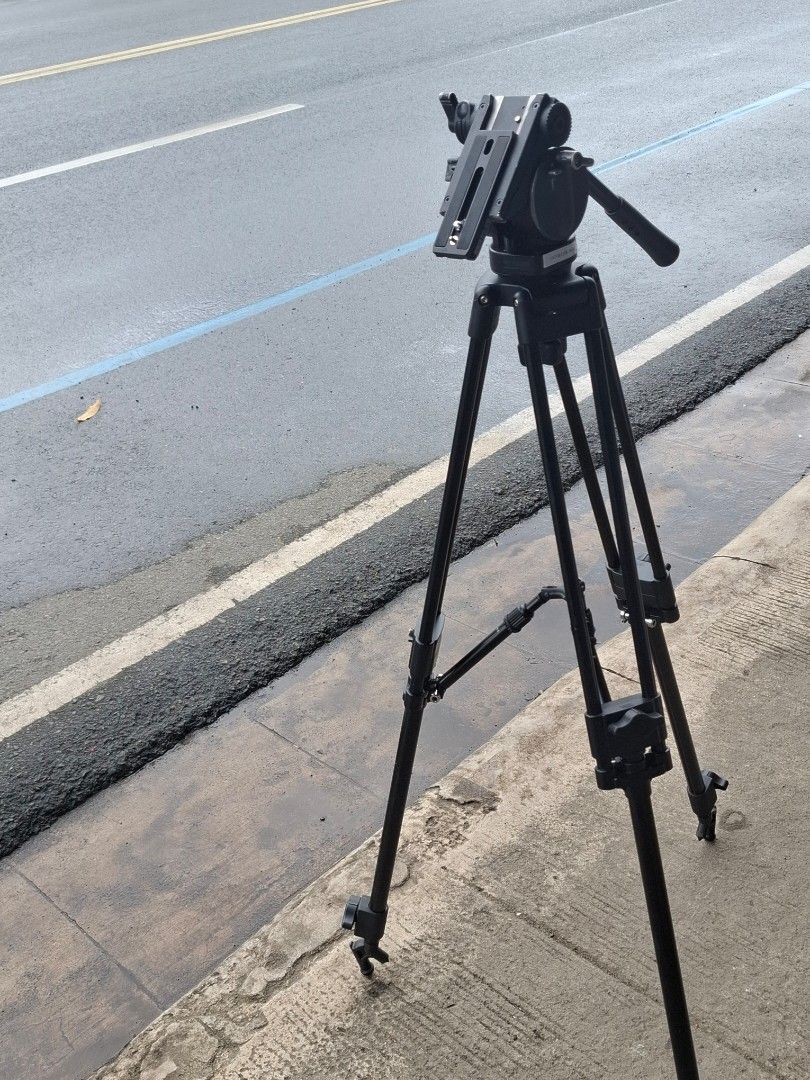 Sony VCT-PG11RMB Professional Video Tripod (Category: Tripods & Monopods) located in Manila. Submitted by rocksolid227 (Listing ID 1467023418, Image 1). Description: Sony VCT-PG11RMB tripod setup. Pan head with adjustable handle included. Sturdy aluminum build with dual leg design for extra stability. Mid-level spreader keeps legs locked in place. Carrying bag included with Sony labeling and tape ID mark. Note the broken plastic piece on one of t