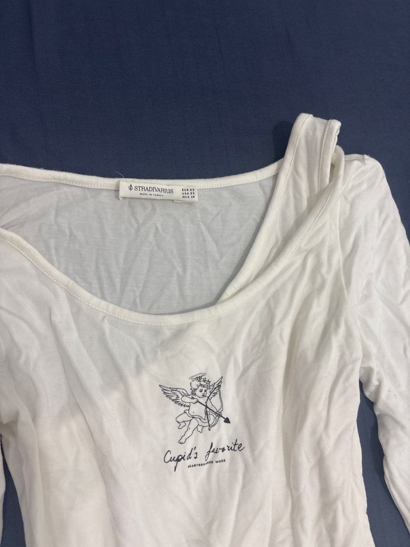 Stradivarius White Cupid Graphic Long Sleeve Top (Category: Longsleeves) located in Makati City. Submitted by blueberrylime (Listing ID 1466975492, Image 2). Description: - Brand: Stradivarius - Size: XS - Color: White - Design: Scoop neckline with asymmetric strap detail, front cupid graphic - Material: Soft, lightweight fabric - Origin: Made in Turkey - Condition: Brand new / Excellent.