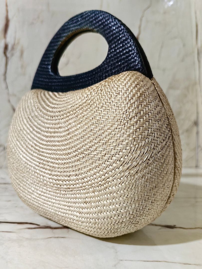 Straw Woven Handbag with Grey Structured Top Handle (Category: Beach Bags) located in Tarlac. Submitted by jeremiah.curator.2026 (Listing ID 1467112006, Image 2). Description: - Natural straw woven body with a trendy curved shape - Stylish dark grey structured top handle - Flat oval base designed to stand firmly on surfaces - Compact handheld size for effortless carrying - Ideal accessory for daytime outings or beach trips.