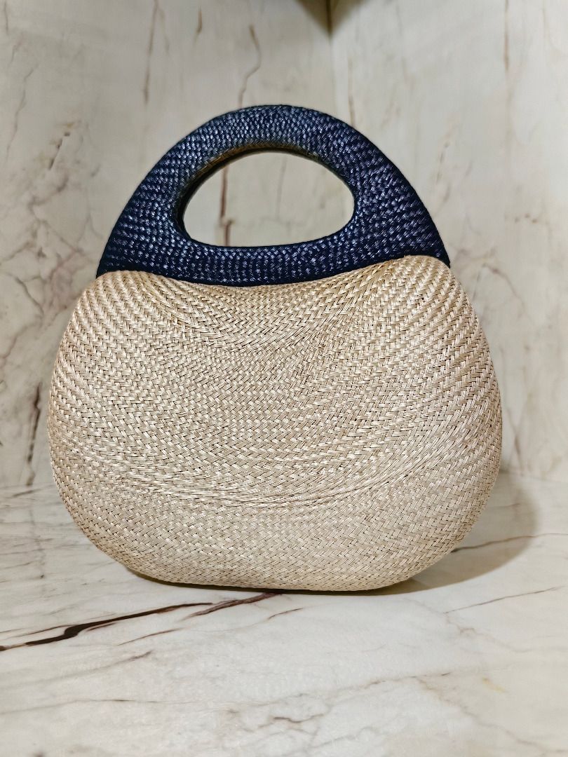 Straw Woven Handbag with Grey Structured Top Handle (Category: Beach Bags) located in Tarlac. Submitted by jeremiah.curator.2026 (Listing ID 1467112006, Image 1). Description: - Natural straw woven body with a trendy curved shape - Stylish dark grey structured top handle - Flat oval base designed to stand firmly on surfaces - Compact handheld size for effortless carrying - Ideal accessory for daytime outings or beach trips.