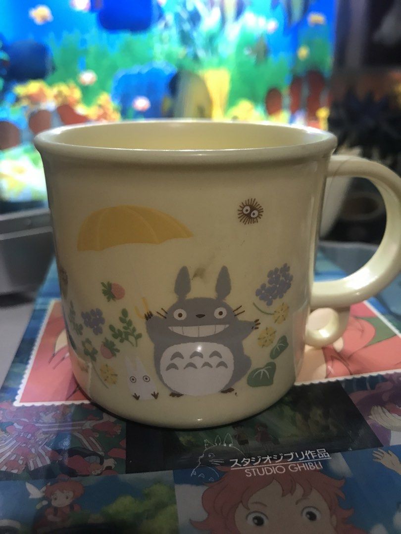 Studio Ghibli My Neighbour Totoro Plastic Mug (Category: Coffee & Tea Tableware) located in Pasig City. Submitted by lilypott (Listing ID 1467039251, Image 1). Description: - 100% Genuine Studio Ghibli merchandise - Cream-coloured plastic mug with Totoro, little white spirit, and yellow umbrella design - Adorned with cute surrounding floral artwork - Lightweight and features a sturdy handle - Standard size, ideal for daily beverages or cute desk 