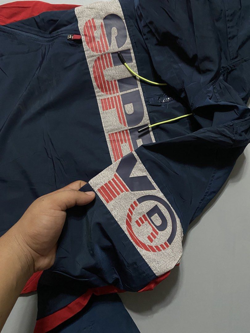 Superdry Hooded Windbreaker Jacket Navy Blue (Category: Coats, Jackets and Outerwear) located in Manila. Submitted by delunakenn94368 (Listing ID 1467141643, Image 3). Description: - Brand: Superdry waterproof - Type: Men's Sport Hooded Jacket / Windbreaker - Color: Navy blue with grey chest panel, red side panels, and bold branding - Features: Neon yellow drawstrings, matching sleeve details, and front zip pockets - Fit: Regular fit - Condition:
