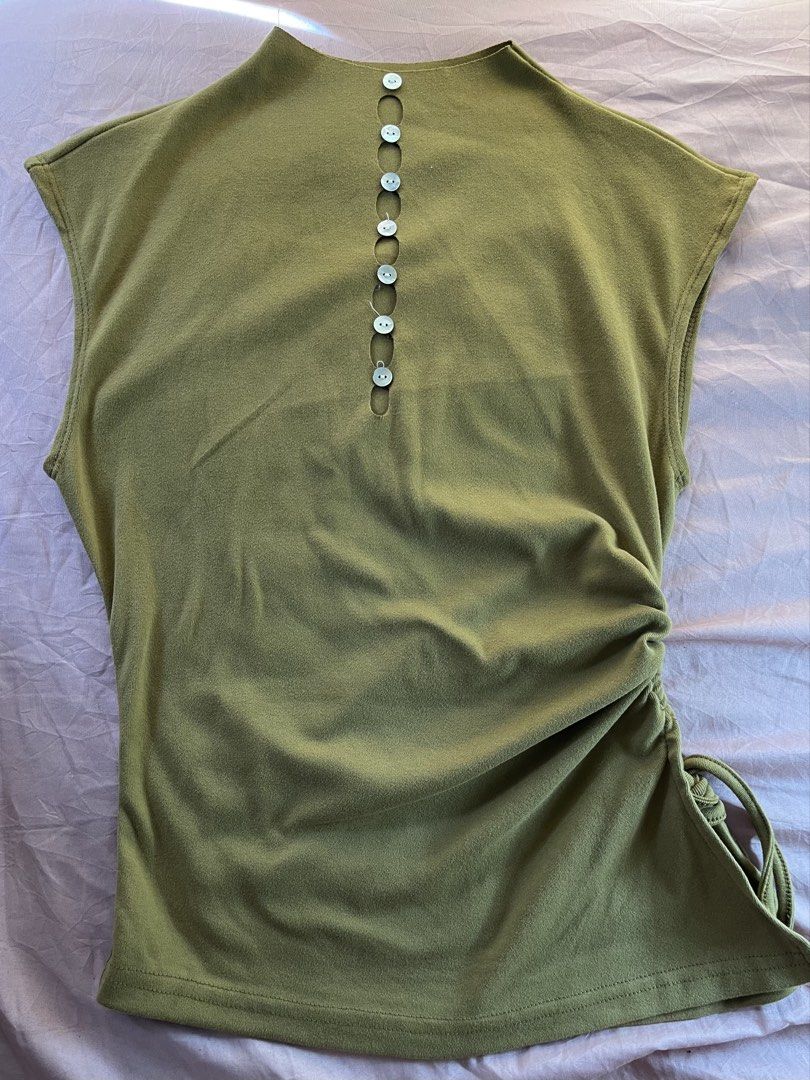 preloved shein turtle neck top (Category: Blouses) located in Bulacan. Submitted by francine.5 (Listing ID 1467037918, Image 1). Description: - Color: Green - Style: Sleeveless mock neck top with front button details - Design: Hollow-out cutouts and adjustable ruched side with drawstring hem - Material: Soft and stretchy fabric - Fit: Casual and great for warm weather - Pairing: Easy to style with denim or white shorts.