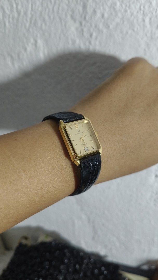 Universal Geneve Quartz Gold toneWatch Black Leather Strap (Category: Women's Watches) located in Taguig. Submitted by mercyeugen28914 (Listing ID 1467031414, Image 3). Description: - Brand: Universal Geneve - Style: Vintage dress watch with gold-tone rectangular case - Dial: Classic champagne dial featuring Roman numeral at 12 and date window at 6 o'clock - Movement: Quartz movement - Strap: Original black leather strap with embossed texture and