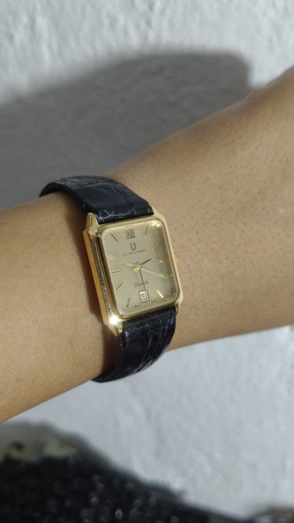Universal Geneve Quartz Gold toneWatch Black Leather Strap (Category: Women's Watches) located in Taguig. Submitted by mercyeugen28914 (Listing ID 1467031414, Image 1). Description: - Brand: Universal Geneve - Style: Vintage dress watch with gold-tone rectangular case - Dial: Classic champagne dial featuring Roman numeral at 12 and date window at 6 o'clock - Movement: Quartz movement - Strap: Original black leather strap with embossed texture and