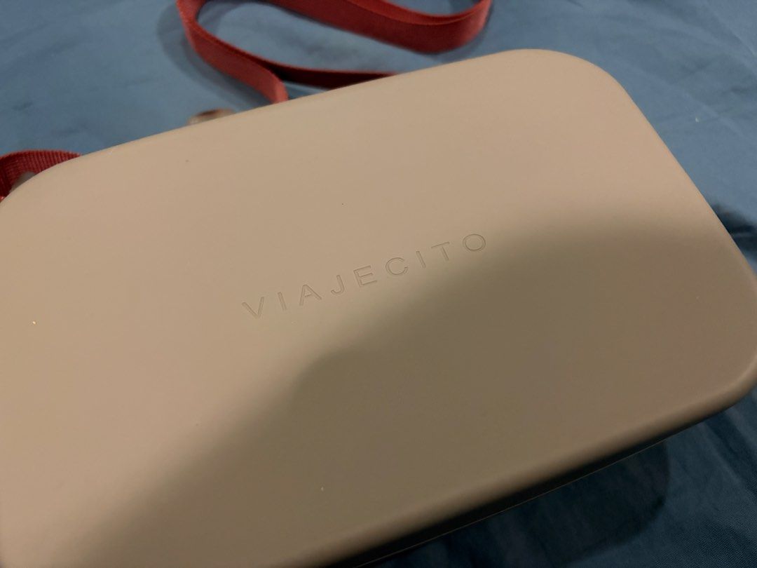 Viajecito Silicone Crossbody Bag (Category: Cross-body Bags) located in Marikina City. Submitted by nj1989 (Listing ID 1467120504, Image 2). Description: - Brand/Model: Viajecito Crossbody Bag Flaw: Discoloration on the lining inside of the bag - Color: Taupe body with a dusty pink strap - Material: Structured, water-resistant hard-shell silicone - Closure: Smooth all-around zipper - Strap: Adjustable woven strap with side loops - Details: Minima