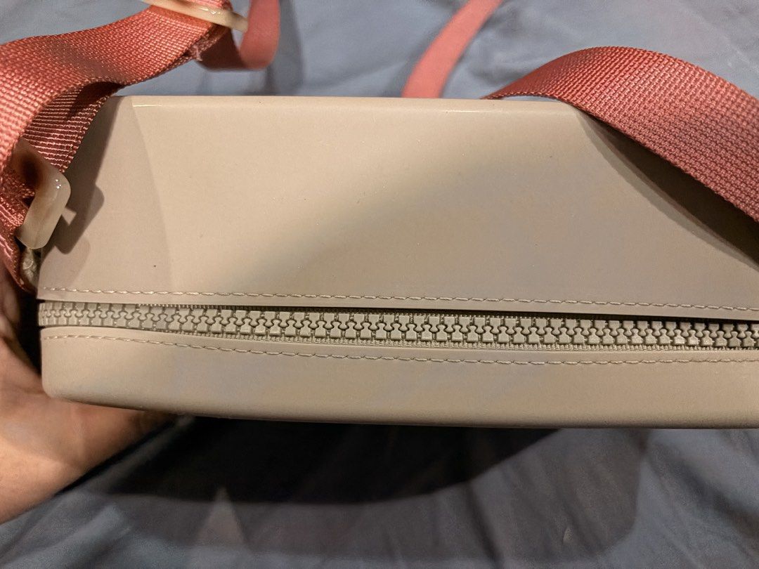 Viajecito Silicone Crossbody Bag (Category: Cross-body Bags) located in Marikina City. Submitted by nj1989 (Listing ID 1467120504, Image 3). Description: - Brand/Model: Viajecito Crossbody Bag Flaw: Discoloration on the lining inside of the bag - Color: Taupe body with a dusty pink strap - Material: Structured, water-resistant hard-shell silicone - Closure: Smooth all-around zipper - Strap: Adjustable woven strap with side loops - Details: Minima