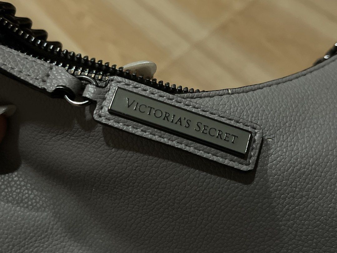 Victoria's Secret Grey Shoulder Bag (Category: Shoulder Bags) located in Manila. Submitted by angelinama02203 (Listing ID 1467123583, Image 2). Description: - Brand: Victoria's Secret - Material: Grey faux leather with dark hardware - Straps: Includes a dark chain strap plus a brand-new detachable long strap still in original plastic - Closure: Secure zip closure with branded pull tab - Interior: Classic striped lining with Victoria's Secret logo