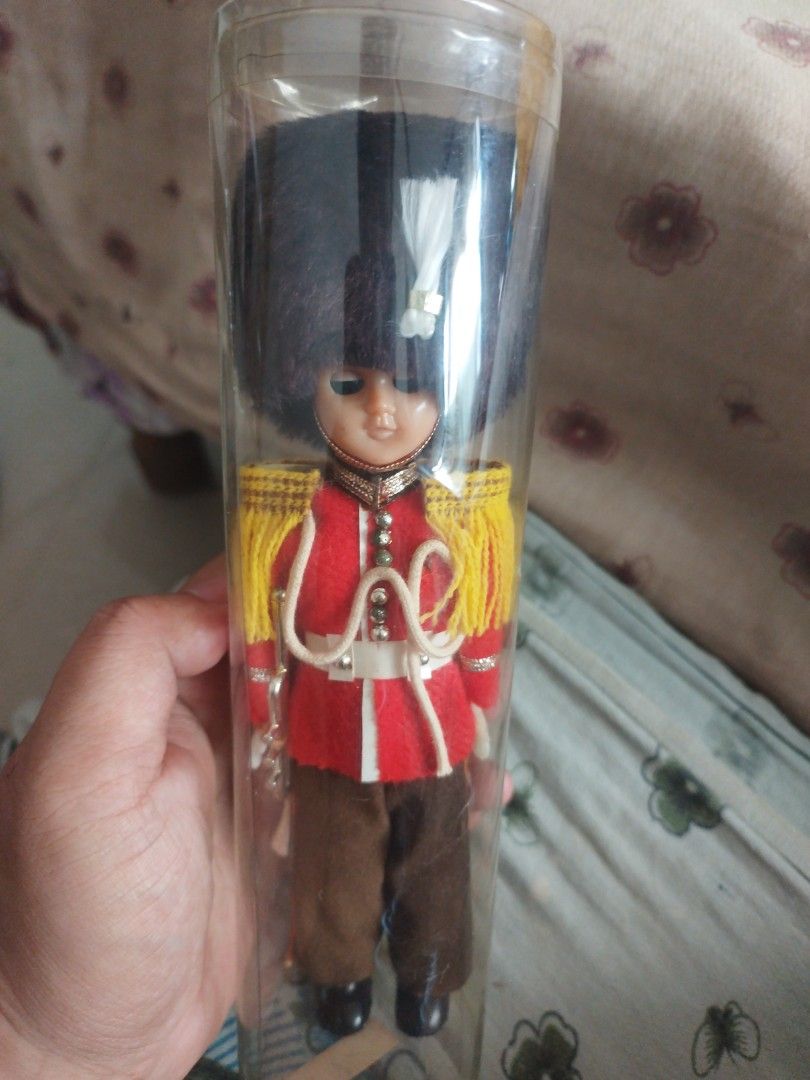 Vintage British Royal palace guard (Category: Vintage Collectibles) located in San Rafael. Submitted by jflshoppe1989 (Listing ID 1467041580, Image 1). Description: Key Features • Design: The doll is dressed as a traditional London / Buckingham Palace Queen's Guard with a red tunic, yellow/gold shoulder accents, a white belt/sash, brown trousers, and a tall black bearskin-style hat with a white plume. • Sleep Eyes: Many of these mid-century retro